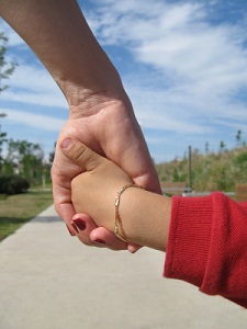 close-up of adult and child's clasped hands